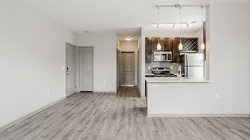 A kitchen with a white countertop and stainless steel appliances is visible through a glass door.